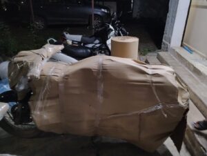 A professional mover in Pune is expertly wrapping a bike with protective foam and cardboard for safe transport to Ahmedabad.